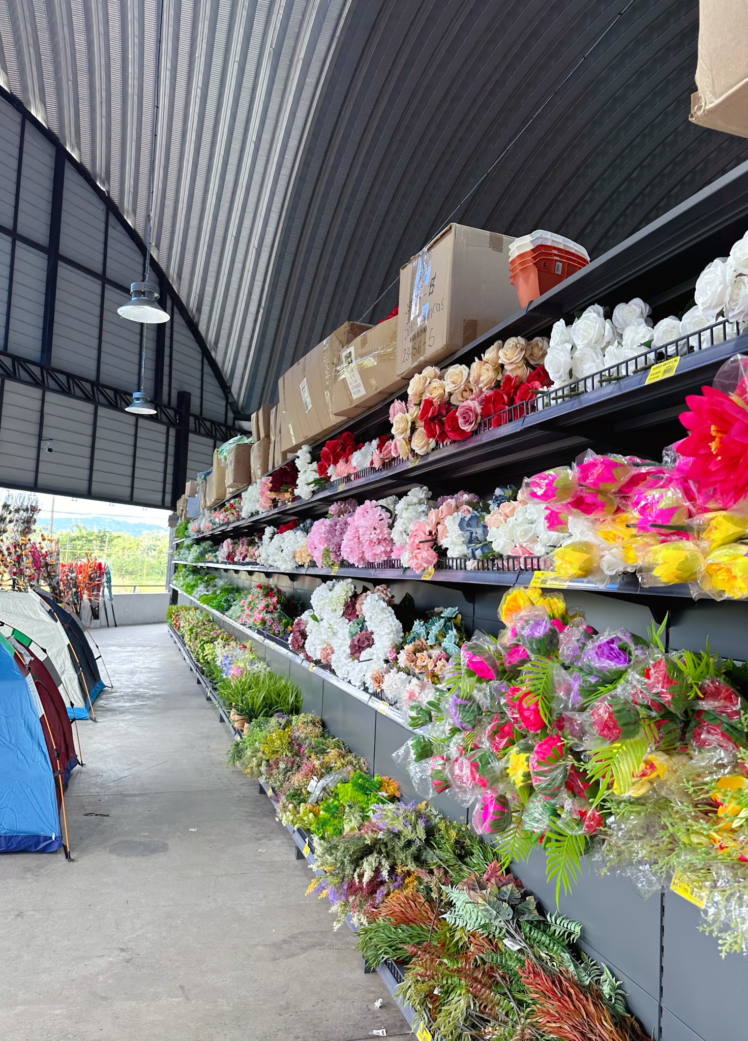 Store aisle with shelves of artificial flowers, plants and seasonal decorations